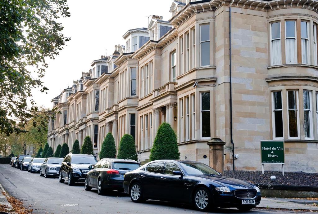 une rangée de voitures garées devant un bâtiment dans l'établissement One Devonshire Gardens a Hotel Du Vin, à Glasgow