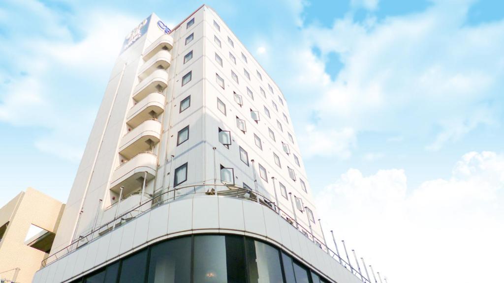 a tall white building with a sky in the background at Center Hotel Mihara in Mihara