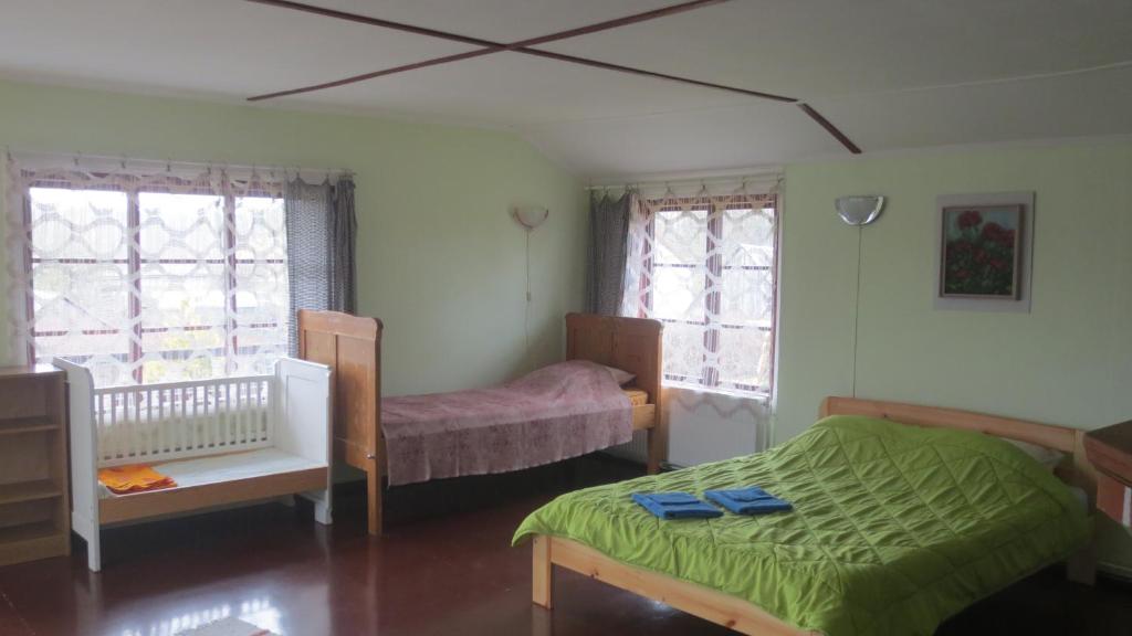een slaapkamer met een bed, een wieg en ramen bij Aizvējā in Pāvilosta