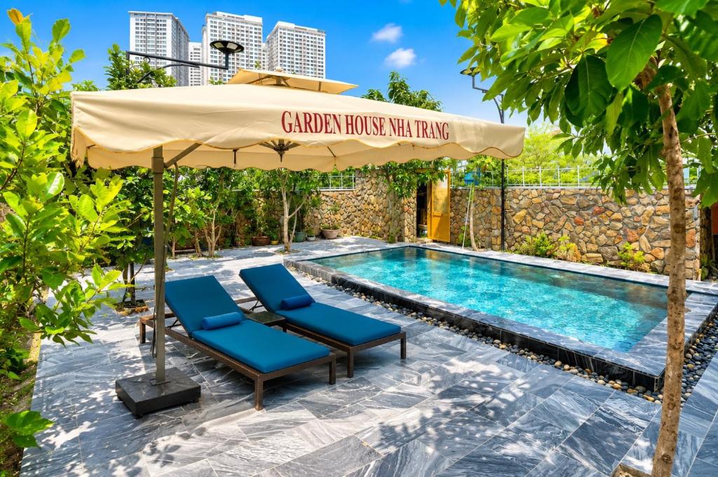 a pool with two chairs and an umbrella next to a swimming pool at Garden House Nha Trang in Nha Trang
