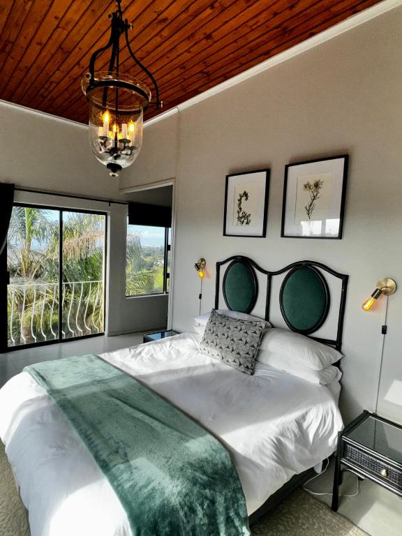 a bedroom with a large bed and a chandelier at Welgemoed Villa in Bellville