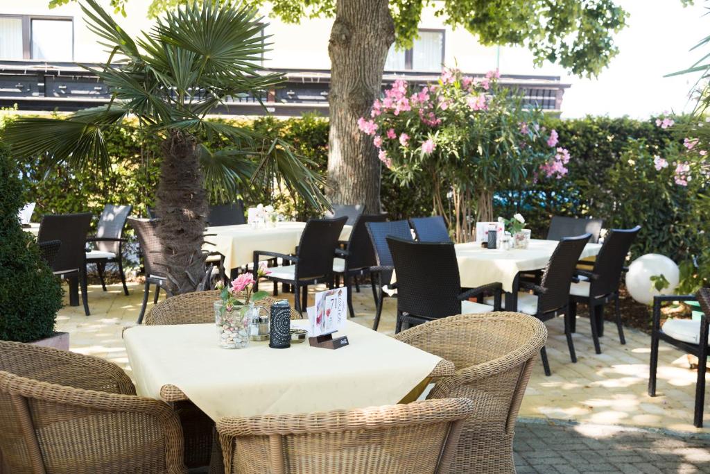 an outdoor patio with tables and chairs and trees at Hotel Restaurant Böck "Roter Hahn" in Sankt Pölten