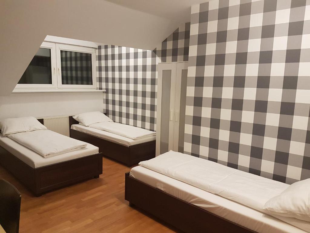 een kamer met 2 bedden en een geruite muur bij Duszka Hostel in Warschau