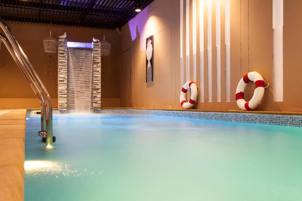 An indoor pool photographed close to the water, with a waterfall feature and safety rings.