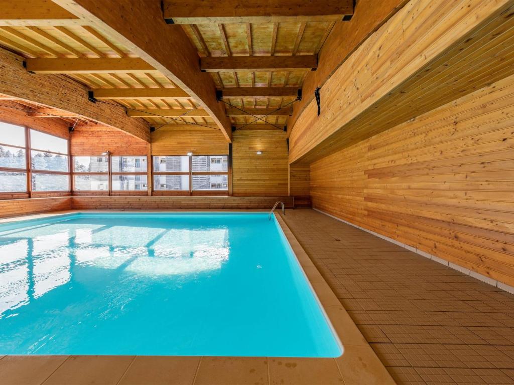une grande piscine intérieure avec des murs en bois dans l'établissement Noemys Ecrin des Neiges, à Chamrousse