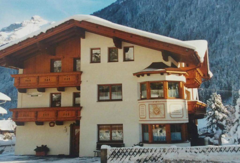 une maison recouverte de neige devant une montagne dans l'établissement Haus Hildegard, à Neustift im Stubaital