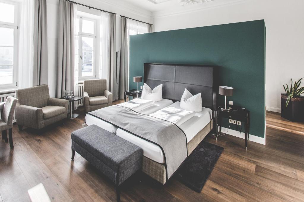 a bedroom with a large bed and a green wall at Hotel Münchner Hof in Altötting