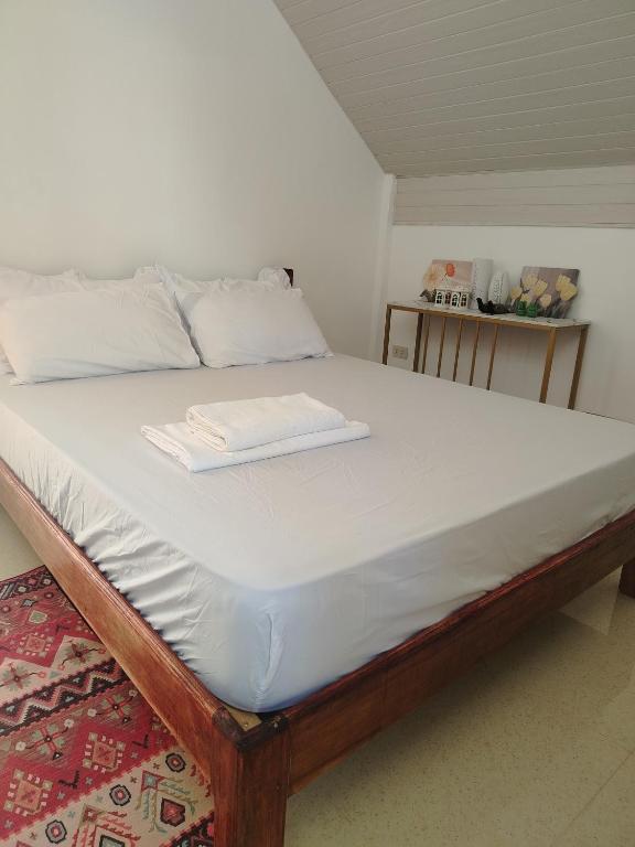 a bed with a wooden frame and white sheets at Mamatitas in San Vicente