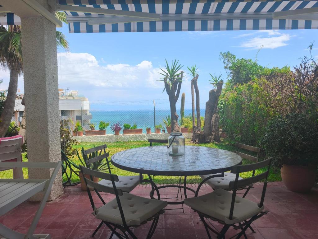 a patio with a table and chairs and the ocean at Calma Bungalow 54b en Urbanización La Roca in Torremolinos