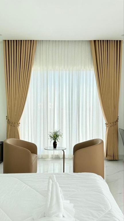 a bedroom with a bed and two chairs and a window at Soksan Nylen Hotel in Kampong Cham