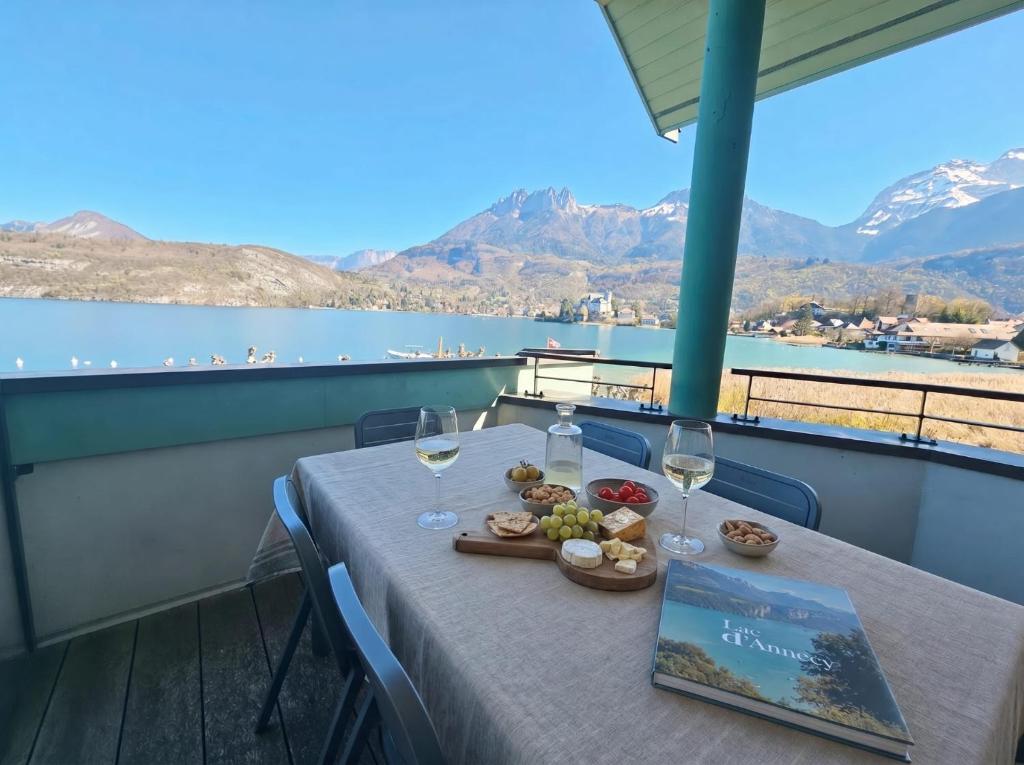 a table with wine glasses and food on a balcony at Appartement 202 Geroli Lac d'Annecy in Duingt