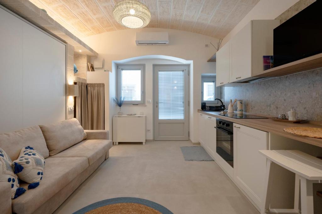 a living room with a couch and a kitchen at Dimora Sofia, Charming House in Savelletri di Fasano