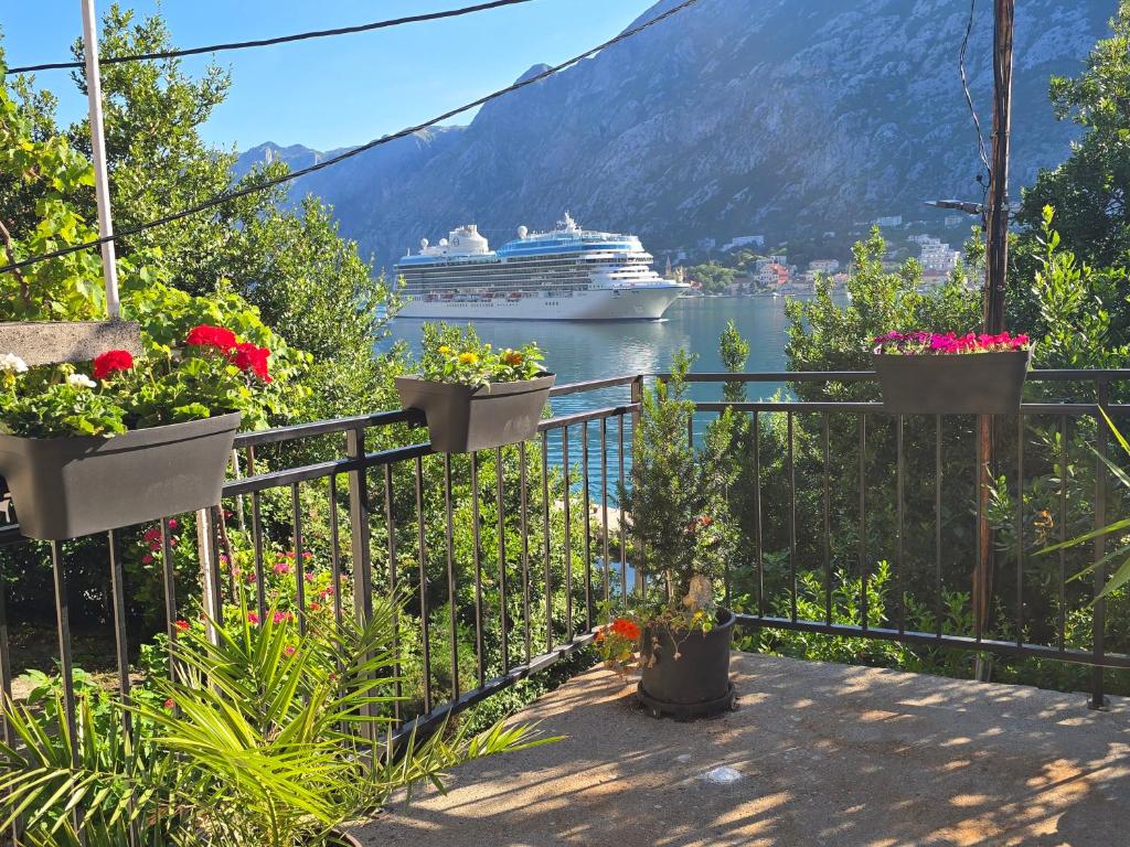 a balcony with flowers and a cruise ship in the water at Apartman Jelena in Kotor