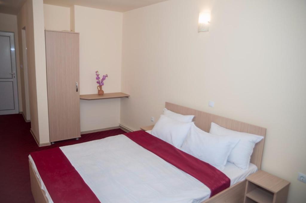 um quarto com uma cama com lençóis brancos e almofadas em Dumbrava Minunata em Braşov