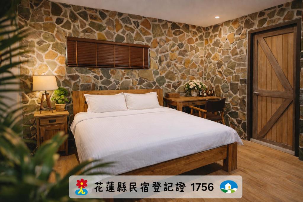 a bedroom with a bed and a stone wall at 皇裔民宿 - 歐式小屋- 無電梯 in Hualien City