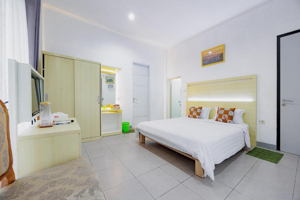 a white bedroom with a large bed and a bathroom at RedDoorz at Batutulis Bogor Villa Papatong by M in Bogor