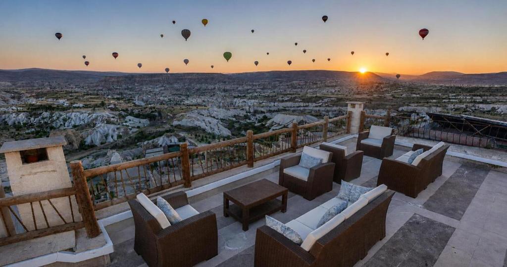a sunset with hot air balloons flying over a city at Wings Cappadocia in Uçhisar