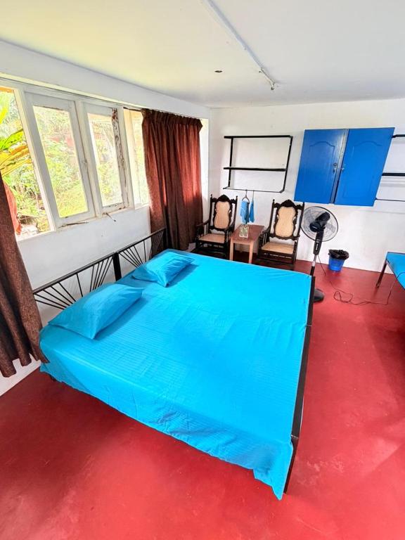 a bedroom with a blue bed and two chairs at Coca Cola Hostel Malabe in Malabe
