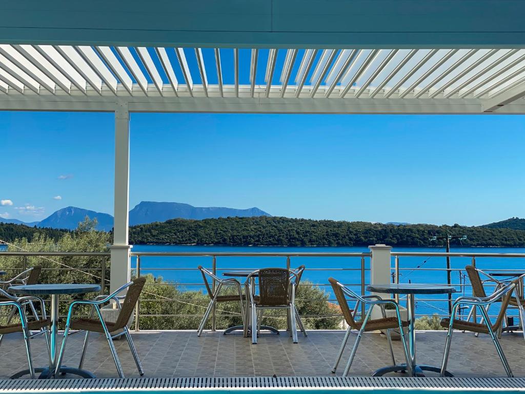 a patio with tables and chairs and a view of the water at Oasis Boutique Hotel in Nydri