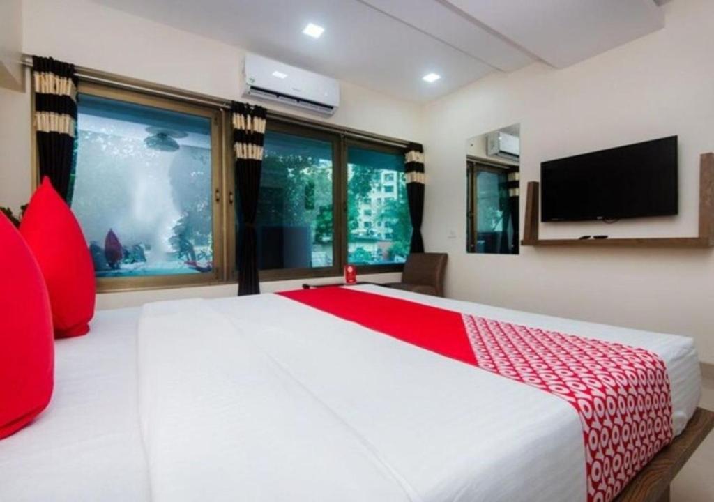 a bedroom with a large white bed with red pillows at Hotel Cliff Hanger in Mumbai