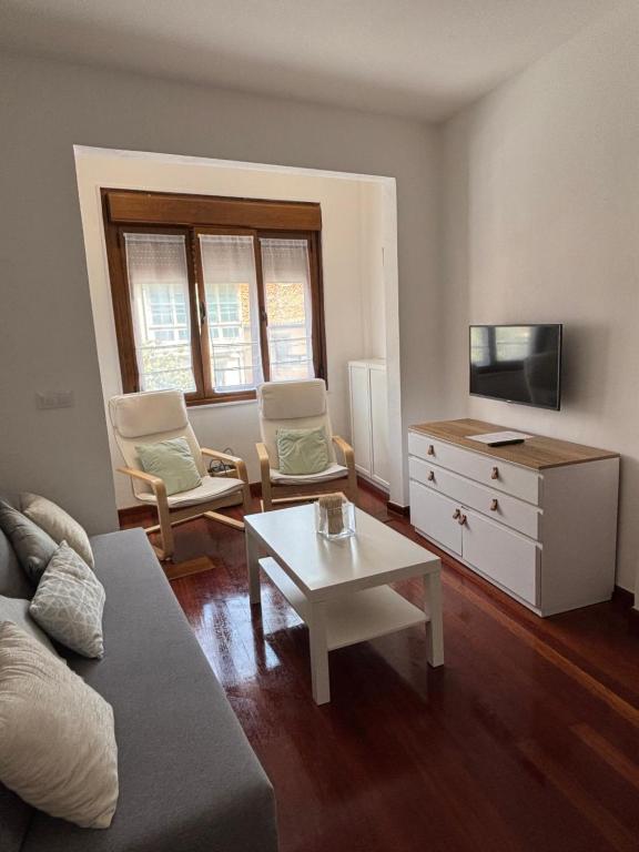 a living room with a couch and a tv and a table at Apartamento Arena in Ribadesella