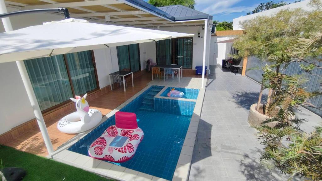 a swimming pool with an umbrella next to a house at บ้านออมPool villa บางแสน sin in Ban Bang Saen (1)