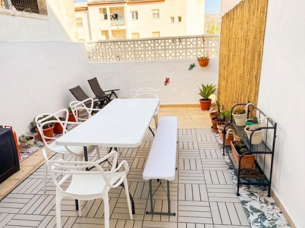 a patio with white tables and chairs on a balcony at Casa De Pueblo Raval in Teulada
