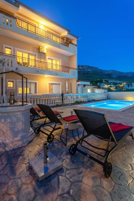 a house with a swimming pool and two chairs at Apartments Dare & Piccolo in Kaštela