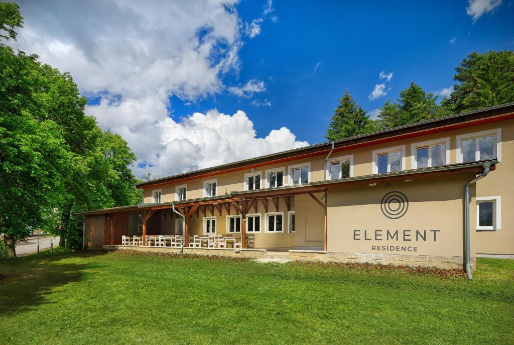 ein Gebäude mit einem Rasen davor in der Unterkunft Element Residence in Lipno nad Vltavou