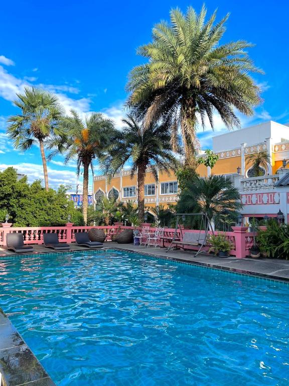 a swimming pool in front of a hotel with palm trees at Rasa Boutique Hotel Chiang Rai in Chiang Rai