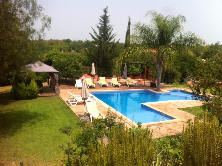 a swimming pool in a yard with chairs and a gazebo at Quinta da Sao Joao - Villa Oliveira in Olhão