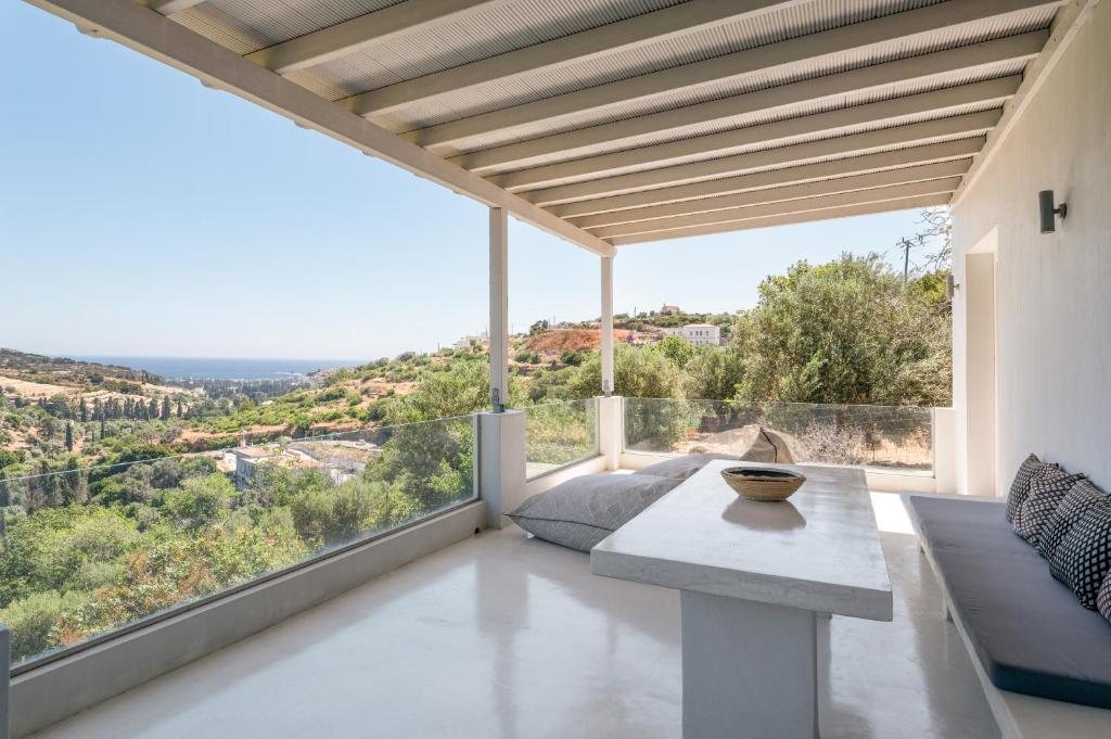 a living room with a table and large windows at Edem Garden Suite in Andros