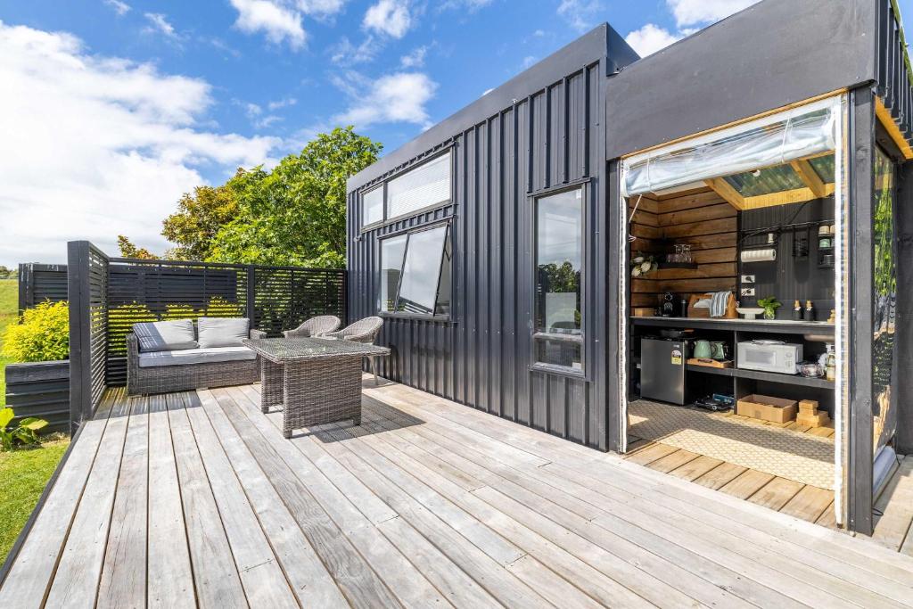 a black tiny house with a wooden deck at Fig Cottage in New Plymouth