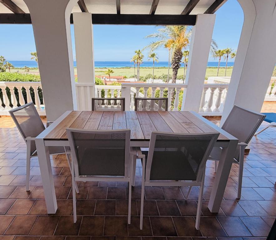 a wooden table and chairs on a porch with the beach at Villa KAKABA in Son Bou