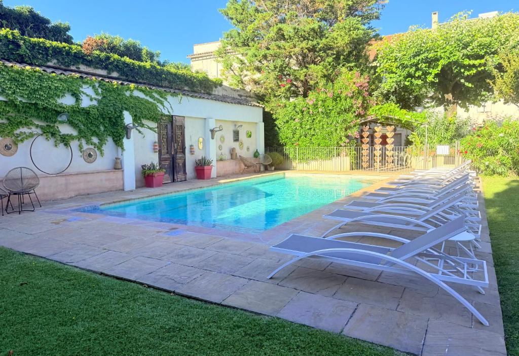 a swimming pool with lounge chairs next to a house at Hôtel La Suite in Villeneuve-lès-Avignon