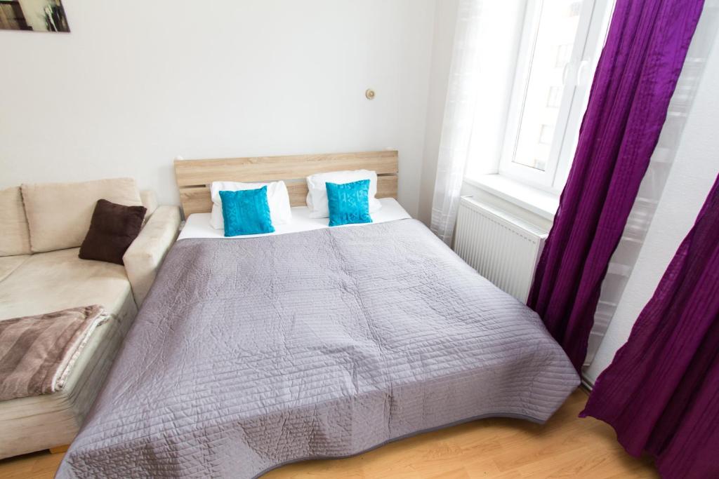 ein Schlafzimmer mit einem Bett mit blauen Kissen und einem Sofa in der Unterkunft Apartment Dieselgasse in Wien