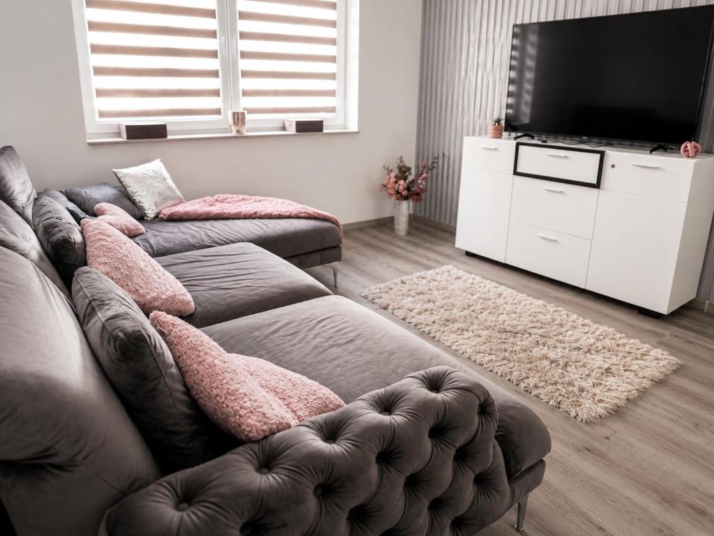 a living room with a couch and a flat screen tv at Móra Apartman in Pécs