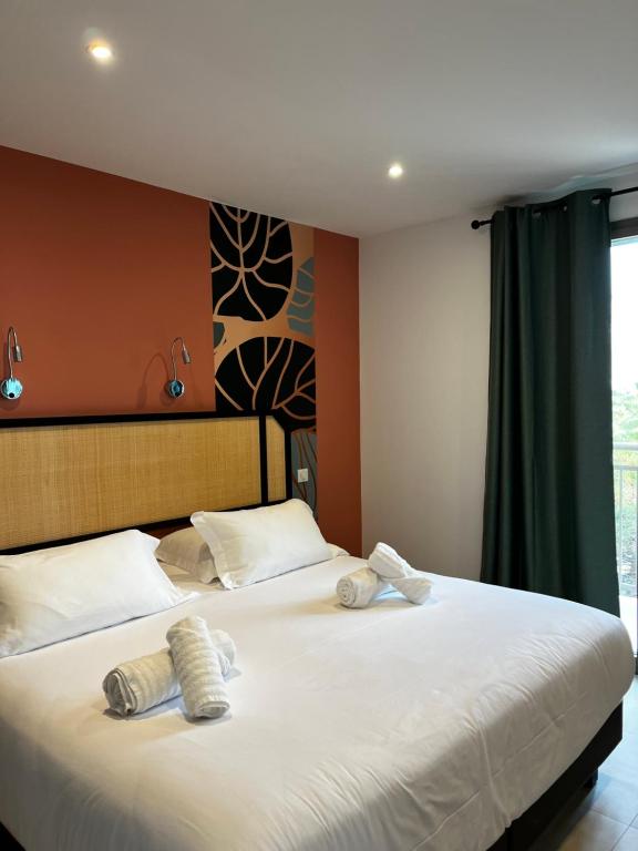 a bedroom with a bed with two towels on it at Hôtel du Golfe Pinarello in Pinarellu