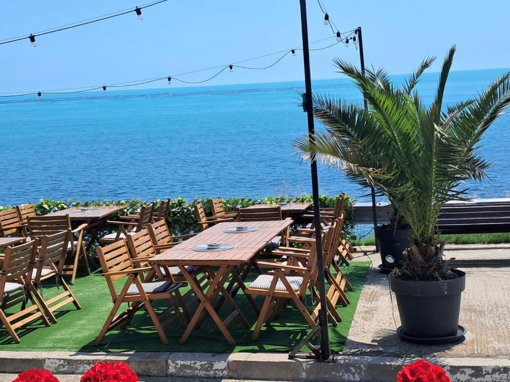 a wooden table and chairs next to the ocean at Hotel Zora by TM in Ravda