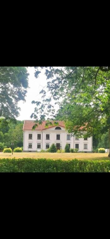 a large white house in the middle of a field at Flishult gård in Vetlanda