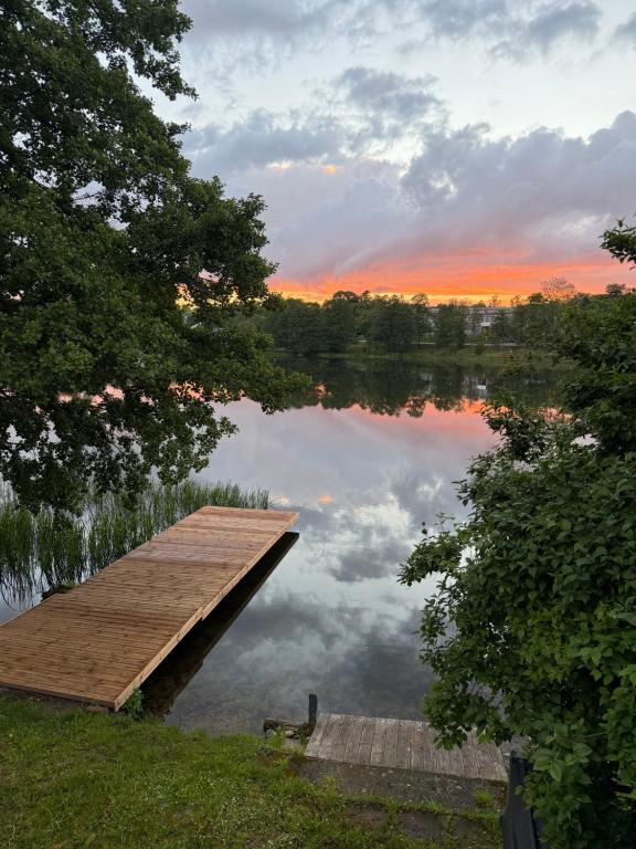 a dock on a lake with a sunset in the background at Las i woda in Przywidz