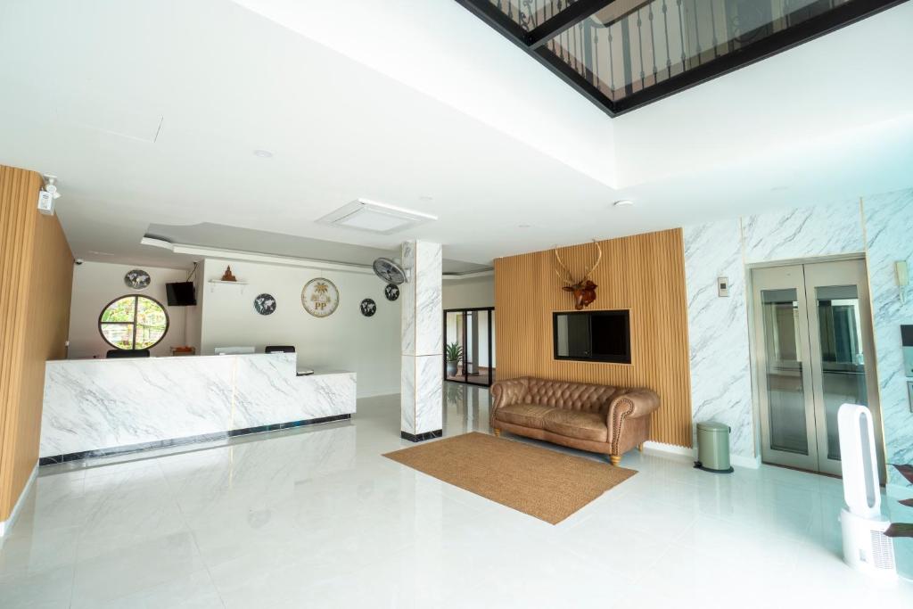A bright hotel lobby with a reception desk, sofa, wall-mounted television and elevator.