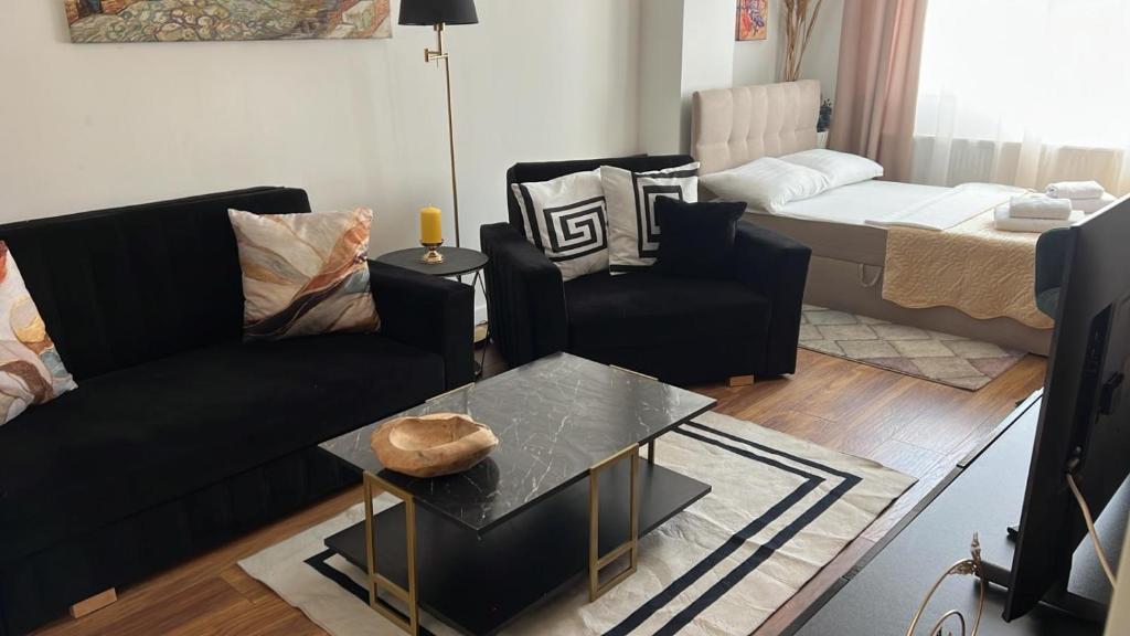 a living room with black couches and a table at Cozy Ivory Studio in Voluntari