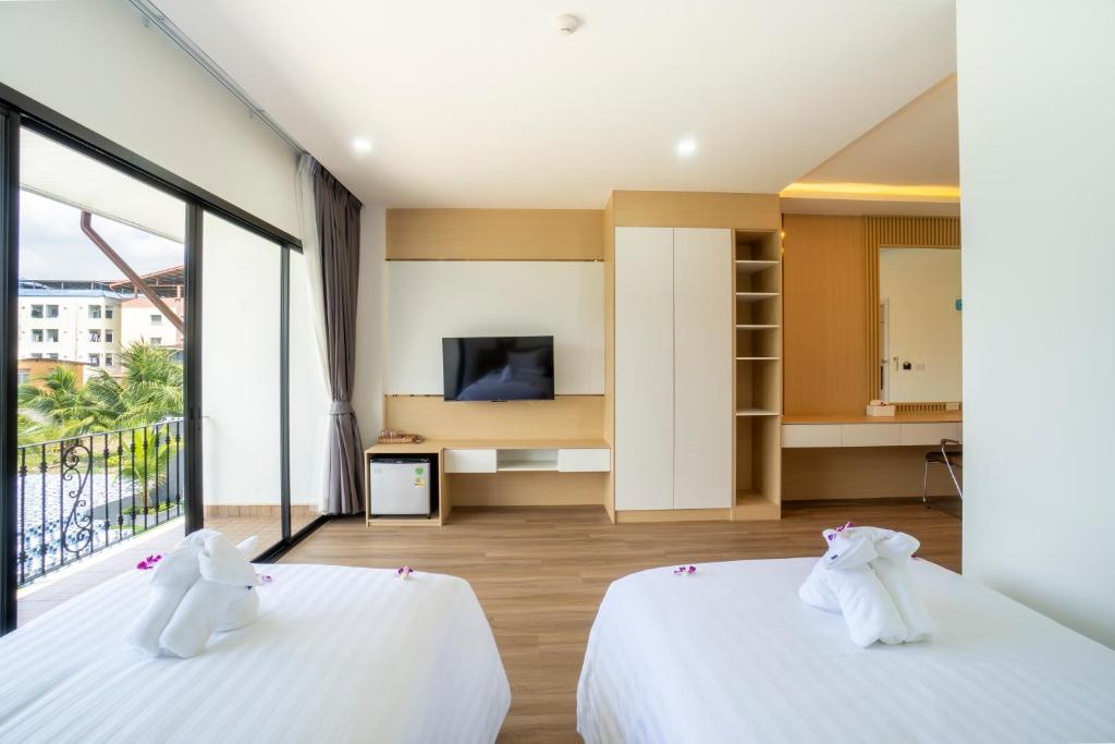 A twin bedroom with two beds, a television, storage, and a balcony opening.