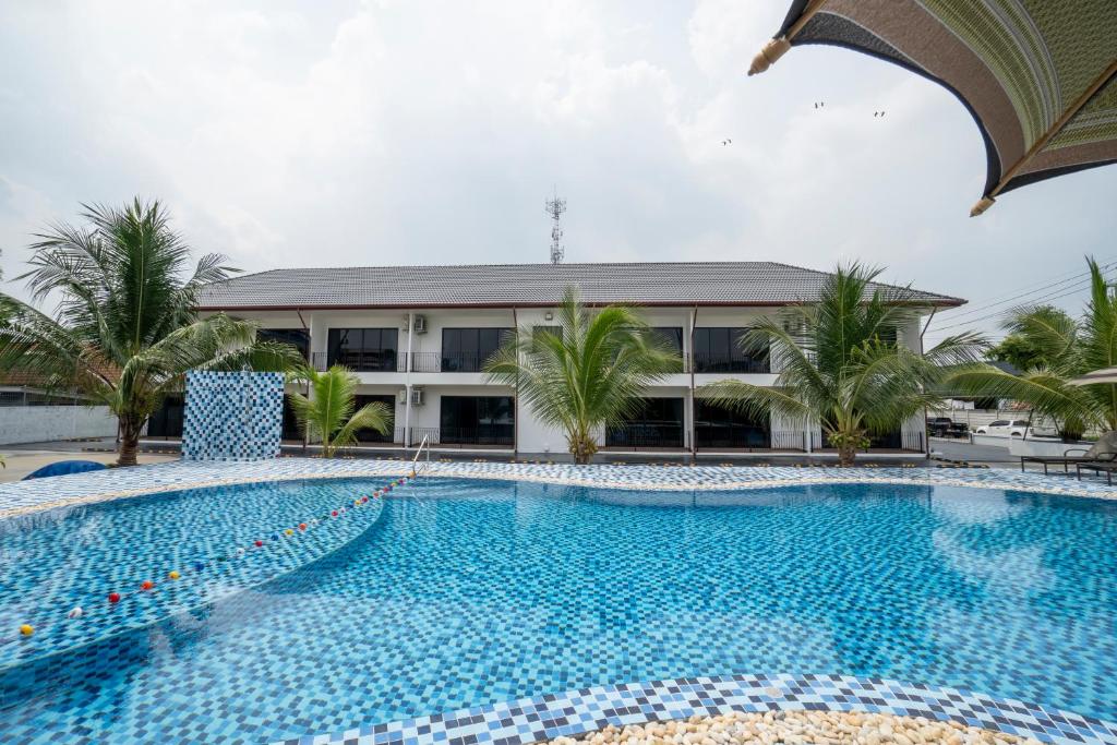 A broad tiled swimming pool facing a low hotel building.