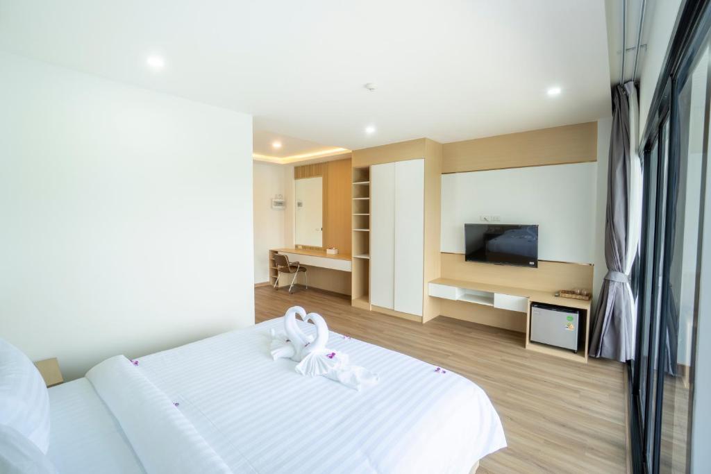 A bright bedroom with a television, vanity, storage, and a large glazed opening.