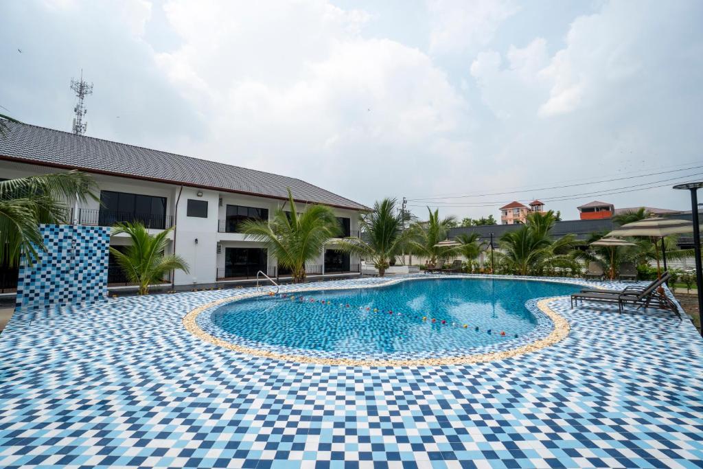 A large outdoor pool surrounded by blue-and-white patterned paving and palm trees.