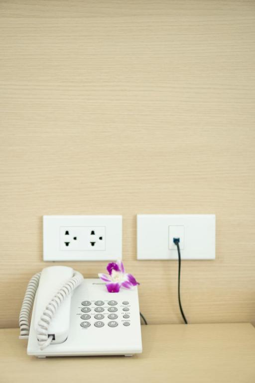 A bedside telephone sits on a small built-in surface beside power and connection outlets.