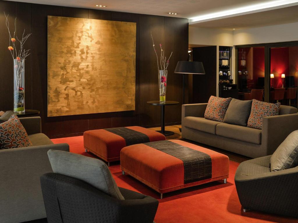a living room with couches and an ottoman at Adagio Grenoble Centre in Grenoble