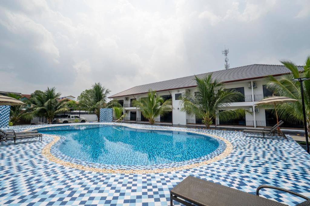 A rounded outdoor pool with loungers, umbrellas and palm-lined hotel buildings.